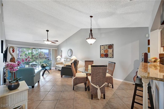 dining room featuring ceiling fan, light tile patterned floors, a textured ceiling, baseboards, and vaulted ceiling