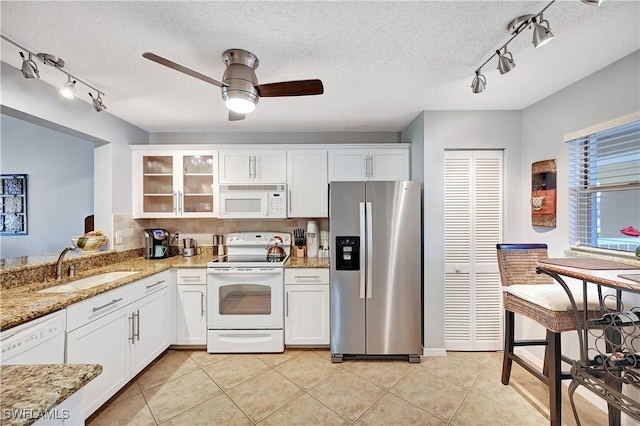 kitchen with white appliances, white cabinets, glass insert cabinets, a sink, and light tile patterned flooring