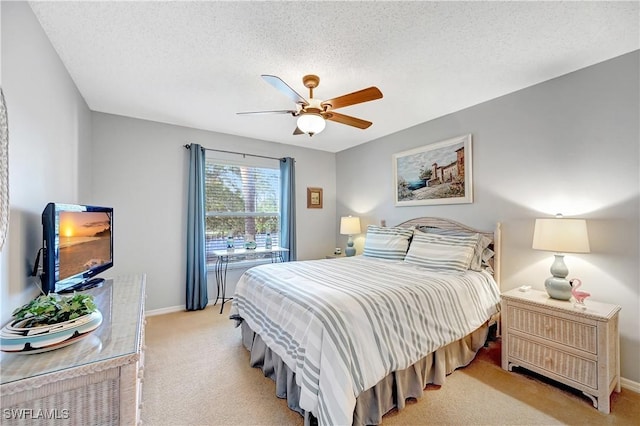 bedroom featuring a ceiling fan, light carpet, a textured ceiling, and baseboards