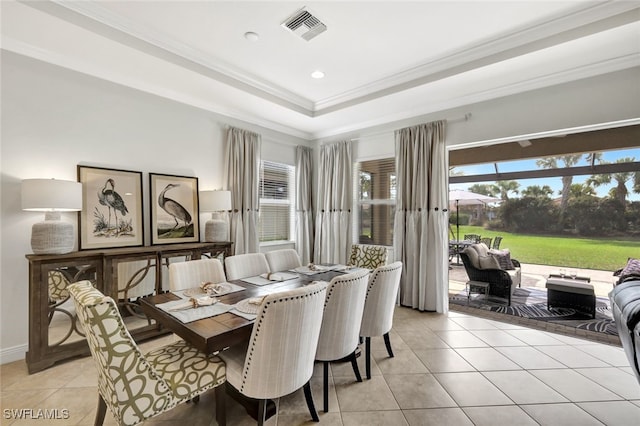 dining room featuring light tile patterned floors, a tray ceiling, visible vents, and crown molding