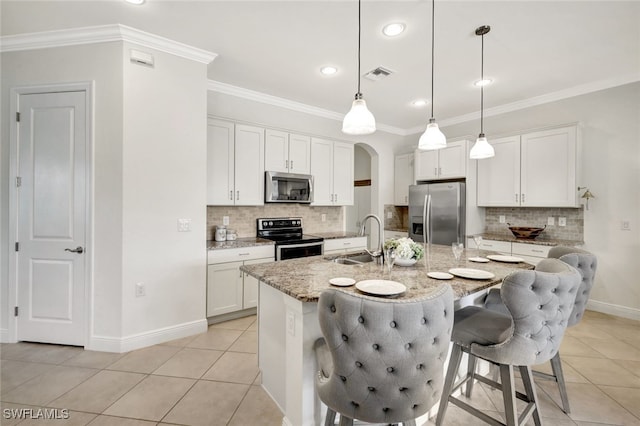 kitchen featuring a kitchen island with sink, stainless steel appliances, a sink, visible vents, and white cabinetry