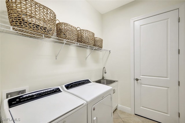 laundry area featuring light tile patterned floors, a sink, baseboards, independent washer and dryer, and cabinet space