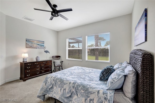 bedroom with light colored carpet, ceiling fan, visible vents, and baseboards