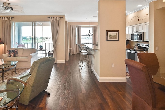 living room with plenty of natural light, a ceiling fan, dark wood finished floors, and crown molding