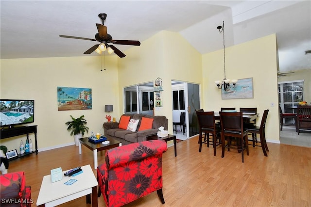 living room with ceiling fan with notable chandelier, high vaulted ceiling, light wood finished floors, and baseboards