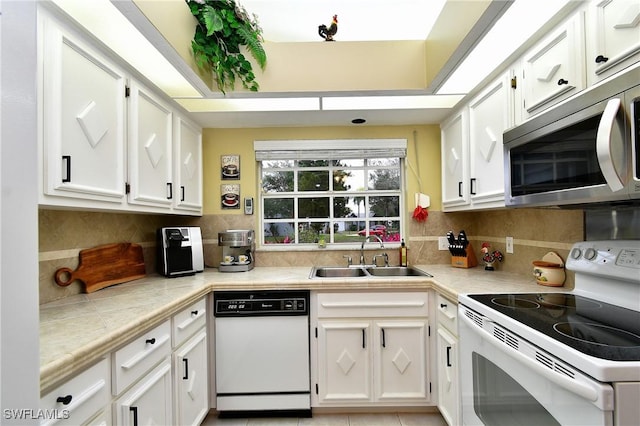 kitchen featuring white appliances, light countertops, and white cabinets