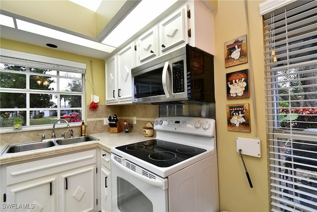 kitchen with white electric stove, stainless steel microwave, light countertops, white cabinetry, and a sink