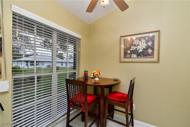 dining space featuring lofted ceiling, ceiling fan, light tile patterned flooring, and baseboards