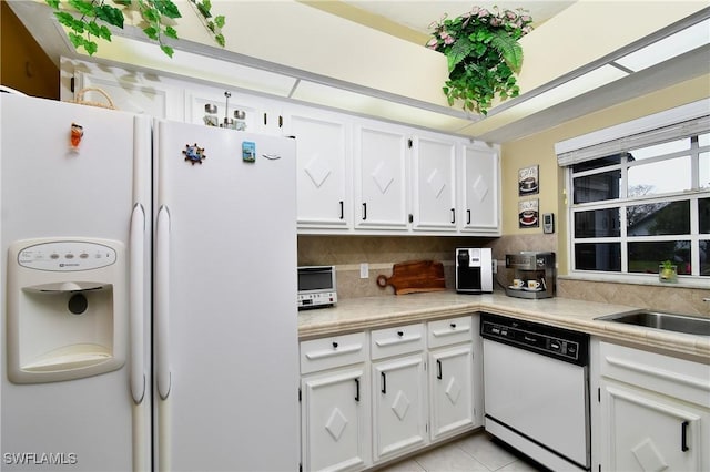 kitchen with white appliances, decorative backsplash, light countertops, white cabinetry, and a sink