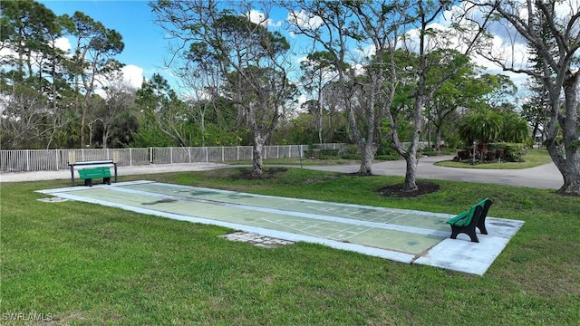 view of community with a yard, fence, and shuffleboard