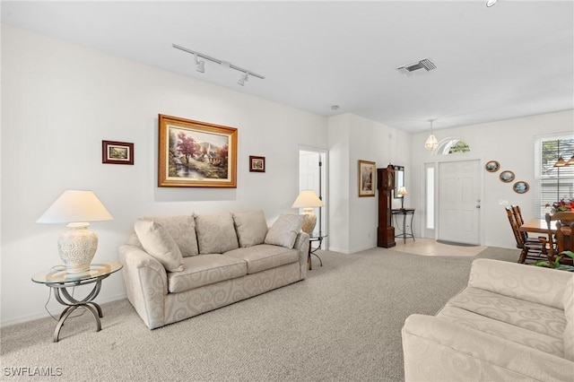 living room featuring rail lighting, baseboards, visible vents, and light colored carpet