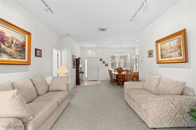 living area with rail lighting, visible vents, a chandelier, and light colored carpet