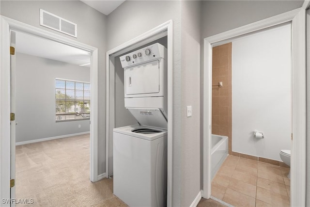 clothes washing area with laundry area, baseboards, visible vents, and stacked washer / dryer