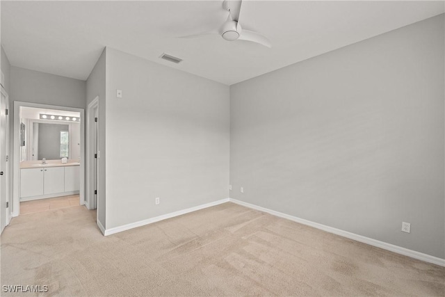 unfurnished bedroom featuring light colored carpet, visible vents, a sink, and baseboards