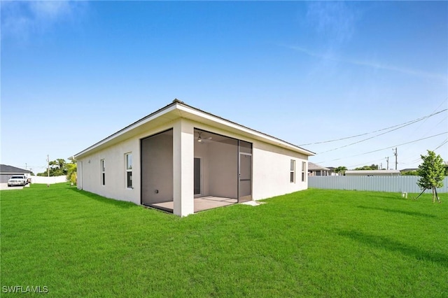 rear view of house featuring stucco siding, fence, a lawn, and a patio