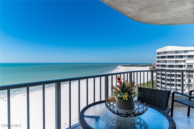 balcony with a water view and a view of the beach