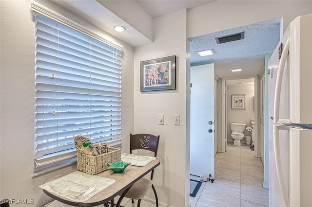 home office featuring a textured ceiling, light tile patterned floors, and visible vents