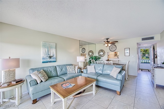 living area with ceiling fan, visible vents, a textured ceiling, and light tile patterned flooring