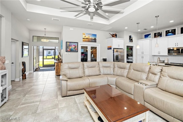 living room featuring a tray ceiling, a towering ceiling, baseboards, and recessed lighting