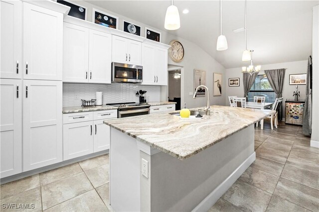 kitchen with stainless steel appliances, a center island with sink, and white cabinetry