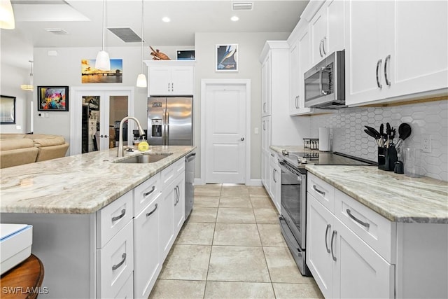 kitchen with white cabinets, decorative light fixtures, a sink, stainless steel appliances, and backsplash