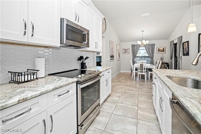 kitchen with white cabinets, stainless steel appliances, a sink, and decorative light fixtures