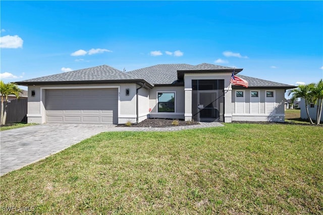 prairie-style home with a garage, decorative driveway, a front lawn, and stucco siding