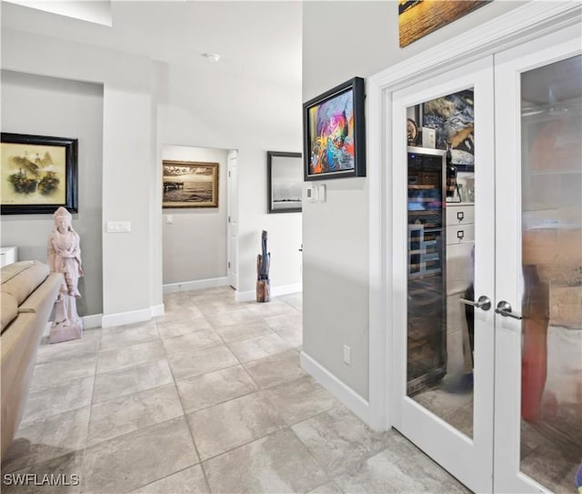 hall with french doors, light tile patterned flooring, and baseboards