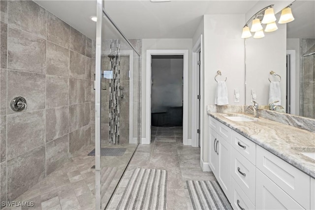 full bath featuring double vanity, walk in shower, a sink, and baseboards