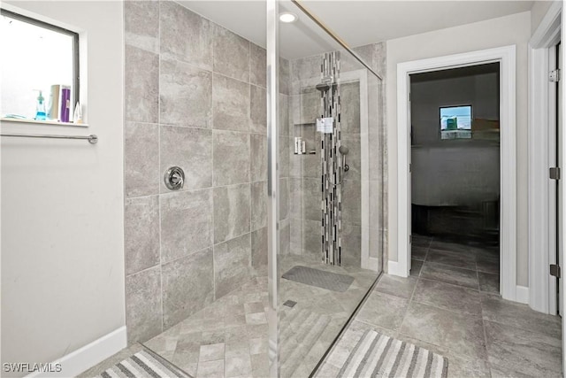 full bath with tiled shower and baseboards