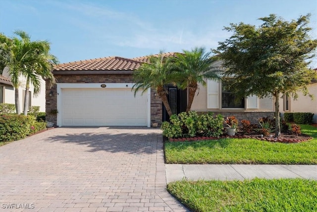 view of front of property featuring decorative driveway, stucco siding, a garage, stone siding, and a tiled roof