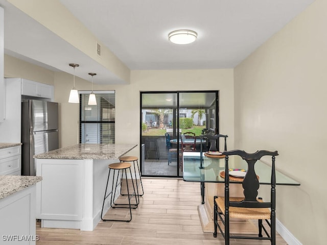 kitchen featuring light stone counters, white cabinets, and freestanding refrigerator