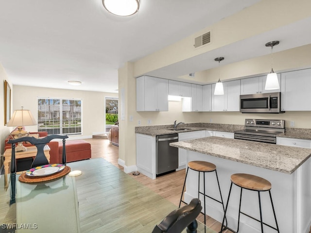 kitchen with visible vents, stainless steel appliances, light wood-style floors, and open floor plan