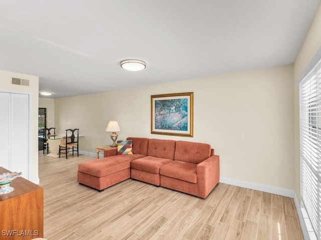 living room featuring visible vents, light wood-style flooring, and baseboards