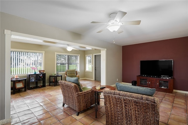 living room featuring ceiling fan, an accent wall, baseboards, and light tile patterned flooring