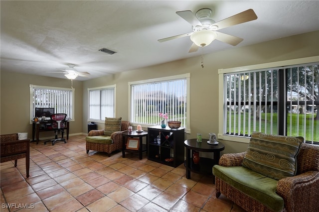 interior space featuring light tile patterned floors, ceiling fan, visible vents, and a textured ceiling