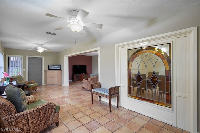 living area with visible vents, ceiling fan, and light tile patterned flooring