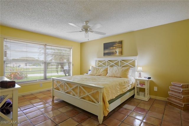 bedroom featuring a ceiling fan, tile patterned flooring, baseboards, and a textured ceiling