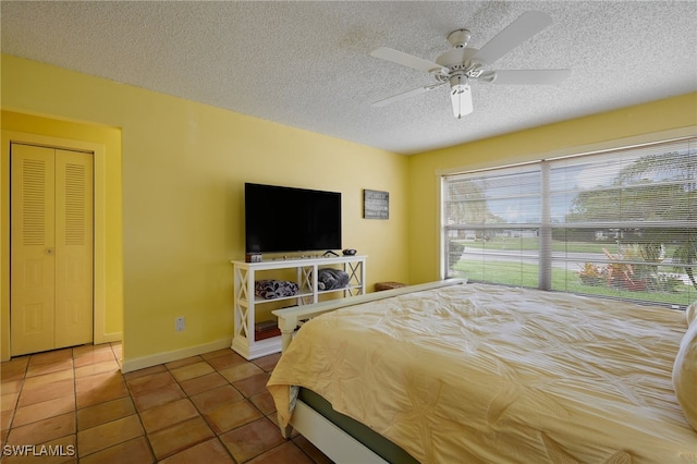 tiled bedroom featuring ceiling fan, a textured ceiling, and baseboards