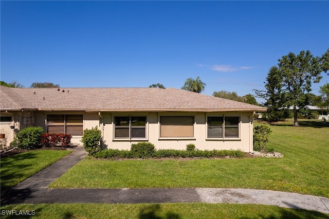 ranch-style home with roof with shingles and a front yard