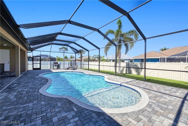 view of pool with a patio area, glass enclosure, a pool with connected hot tub, and a fenced backyard