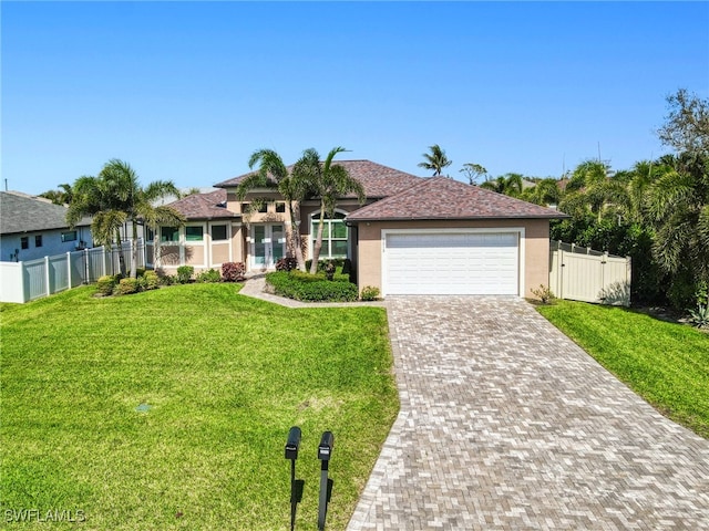 ranch-style house featuring an attached garage, fence, decorative driveway, and a front yard