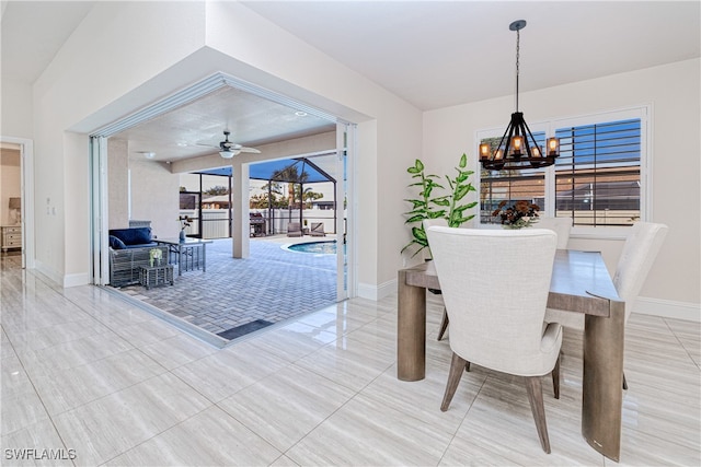 dining room featuring ceiling fan with notable chandelier and baseboards