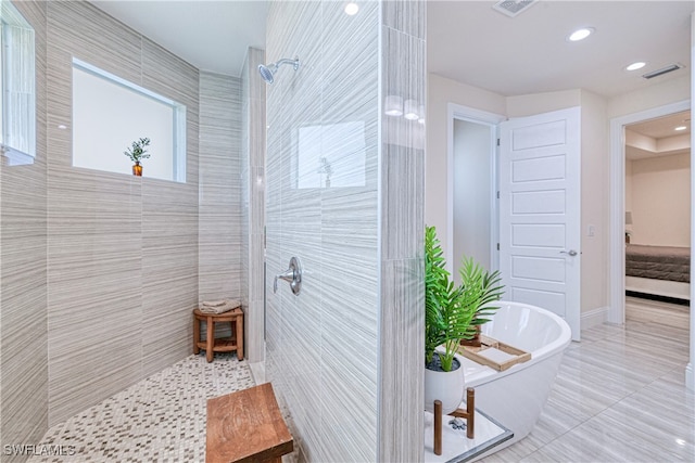 ensuite bathroom with a walk in shower, a freestanding tub, and visible vents