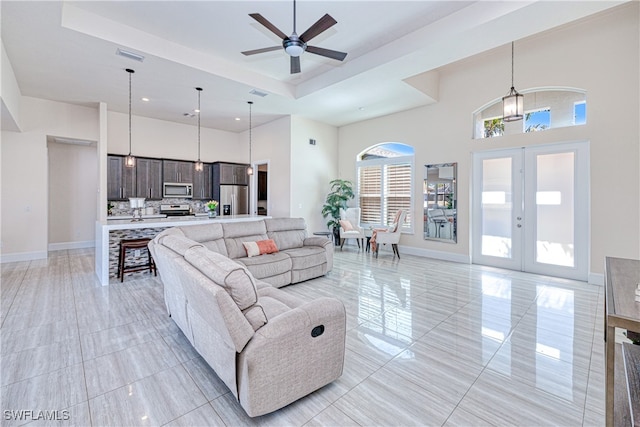 living room featuring a high ceiling, visible vents, baseboards, french doors, and a tray ceiling