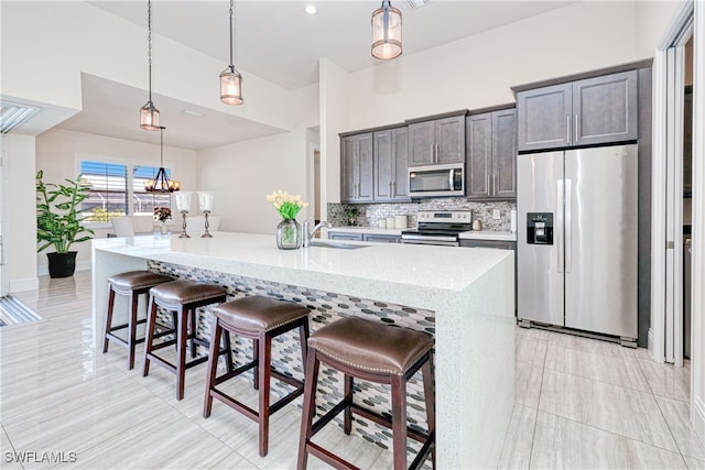 kitchen with an island with sink, appliances with stainless steel finishes, a breakfast bar, and decorative light fixtures