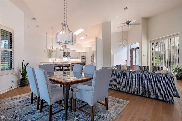 dining space featuring visible vents, baseboards, dark wood finished floors, a high ceiling, and ceiling fan with notable chandelier