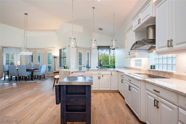 kitchen featuring black electric stovetop, extractor fan, white cabinetry, and pendant lighting