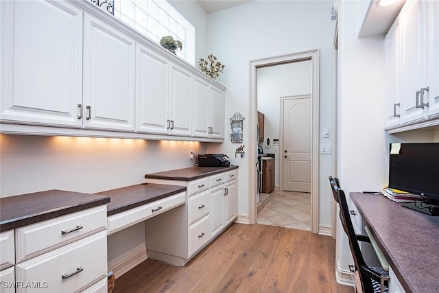 kitchen featuring dark countertops, built in study area, and white cabinetry