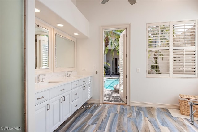 full bathroom with double vanity, wood finished floors, a sink, and baseboards